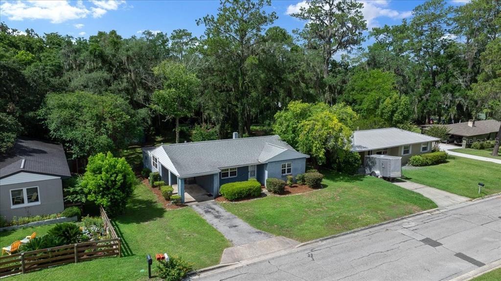 An aerial view shows a blue single-story house with a carport and a large yard — 1142 NE 8TH STREET, OCALA, FL