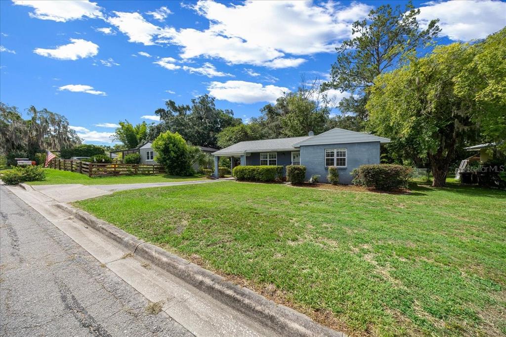 A single-story blue house with a front porch sits on a grassy lot — 1142 NE 8TH STREET, OCALA, FL