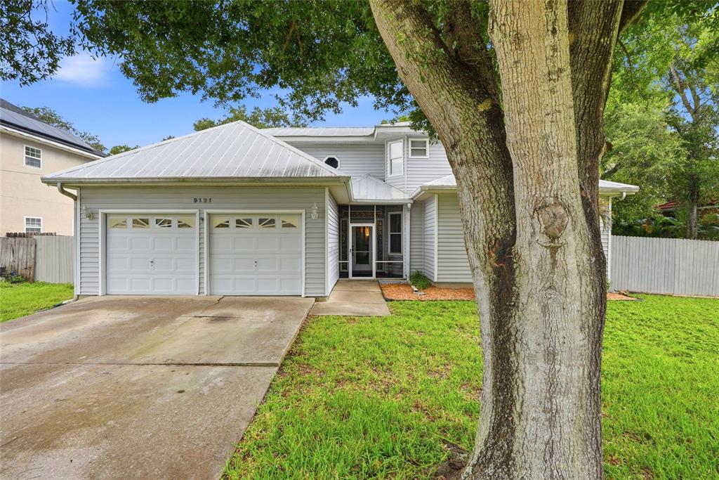 A two-story house with light gray siding, a metal roof, and a two-car garage — 9121 65TH STREET N, PINELLAS PARK, FL