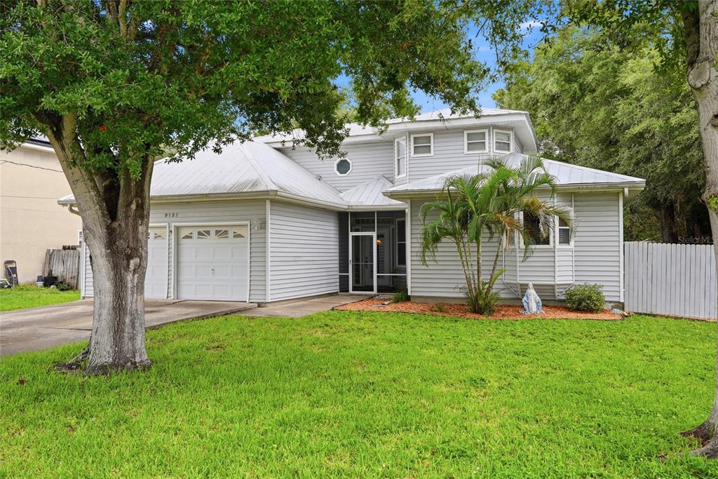 A two-story light gray house with a metal roof, a two-car garage, and a front lawn — 9121 65TH STREET N, PINELLAS PARK, FL