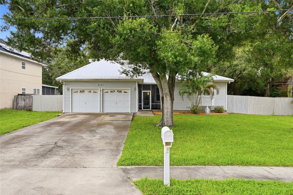 A single-story house with a two-car garage, a concrete driveway, and a large front tree — 9121 65TH STREET N, PINELLAS PARK, FL