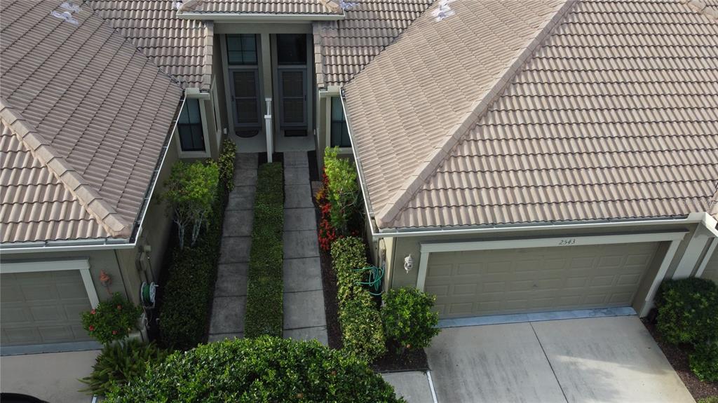 An aerial view shows two adjacent townhomes with beige tile roofs and shared walkways — 2543 GLORIOSA DRIVE, PALM HARBOR, FL