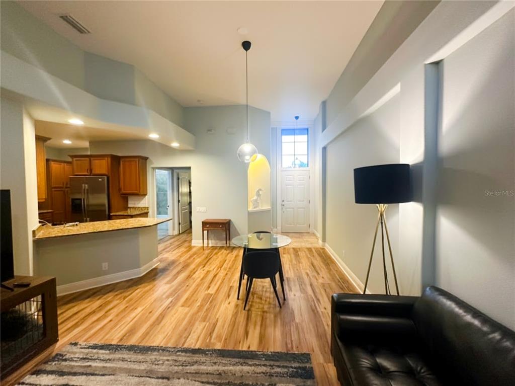A living and dining area features light blue walls, wood flooring, and a high ceiling — 2543 GLORIOSA DRIVE, PALM HARBOR, FL