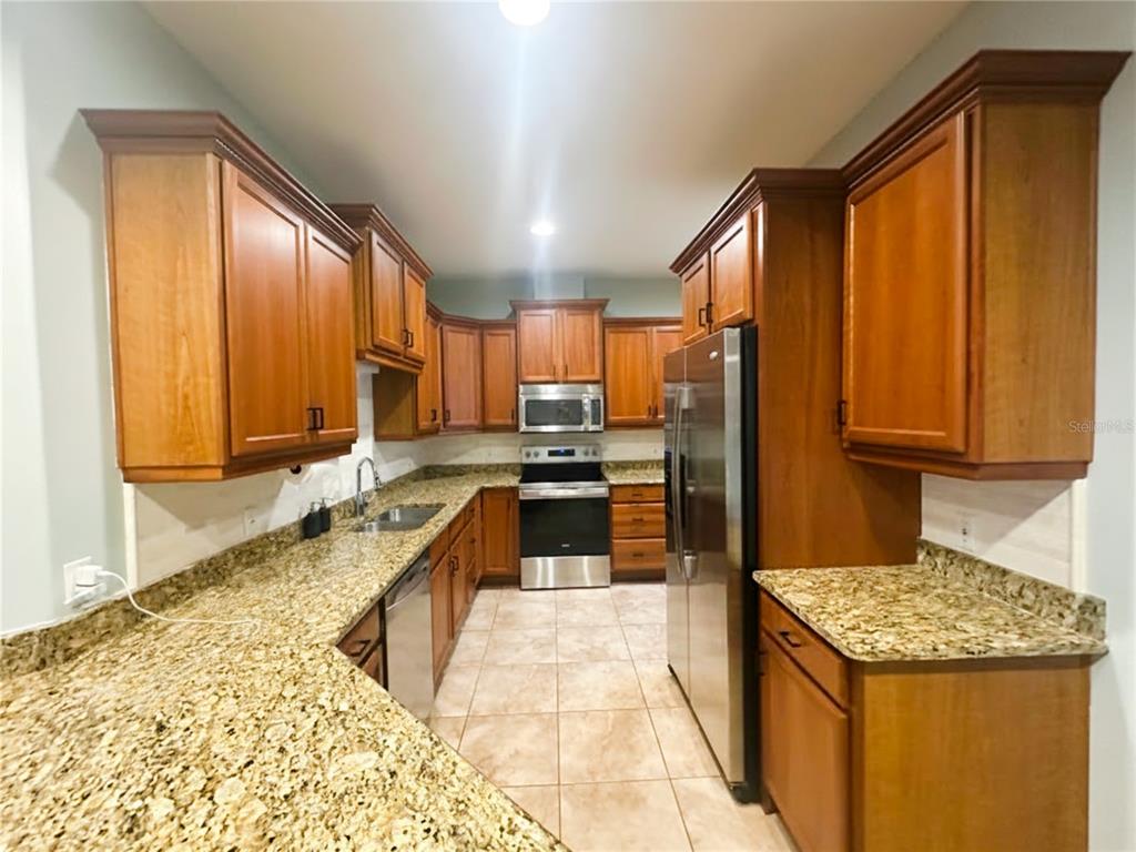 A kitchen with wood cabinets, granite countertops, stainless steel appliances, and tile flooring — 2543 GLORIOSA DRIVE, PALM HARBOR, FL