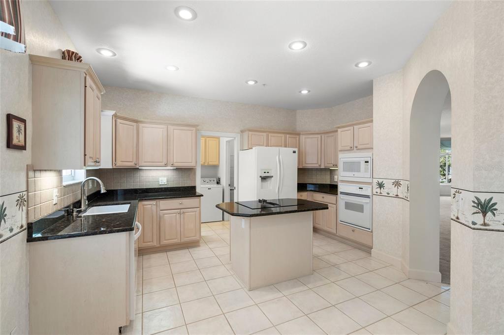 A kitchen with light wood cabinets, black granite countertops, a center island, and tile flooring — 3954 HAMILTON CLUB CIRCLE UNIT 14, SARASOTA, FL