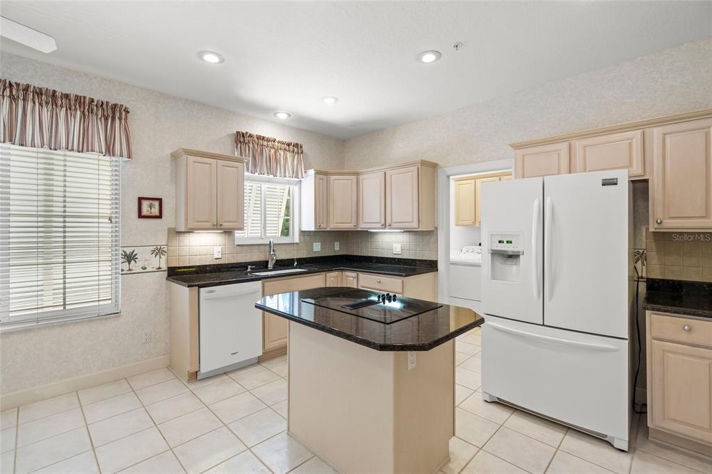 A kitchen with light wood cabinets, dark granite countertops, white appliances, and tiled flooring — 3954 HAMILTON CLUB CIRCLE UNIT 14, SARASOTA, FL