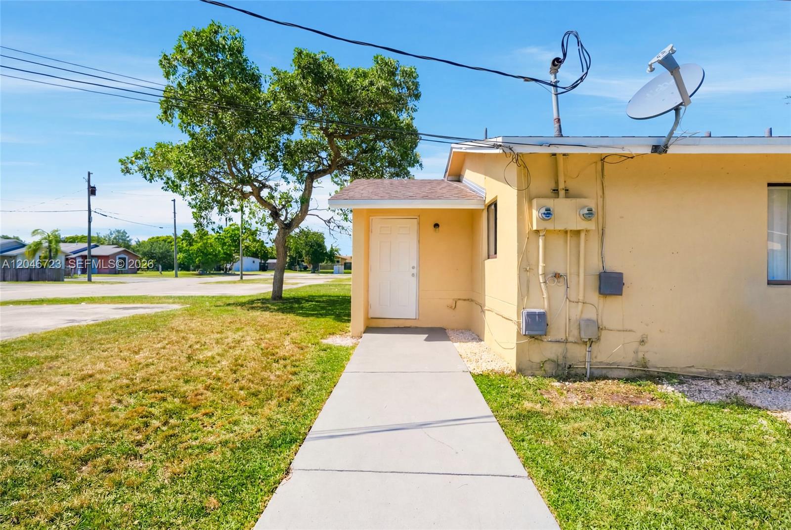 A concrete walkway leads to the side entrance of a yellow stucco house — 20117 SW 88th Ct, Cutler Bay FL 33189, CUTLER BAY, FL
