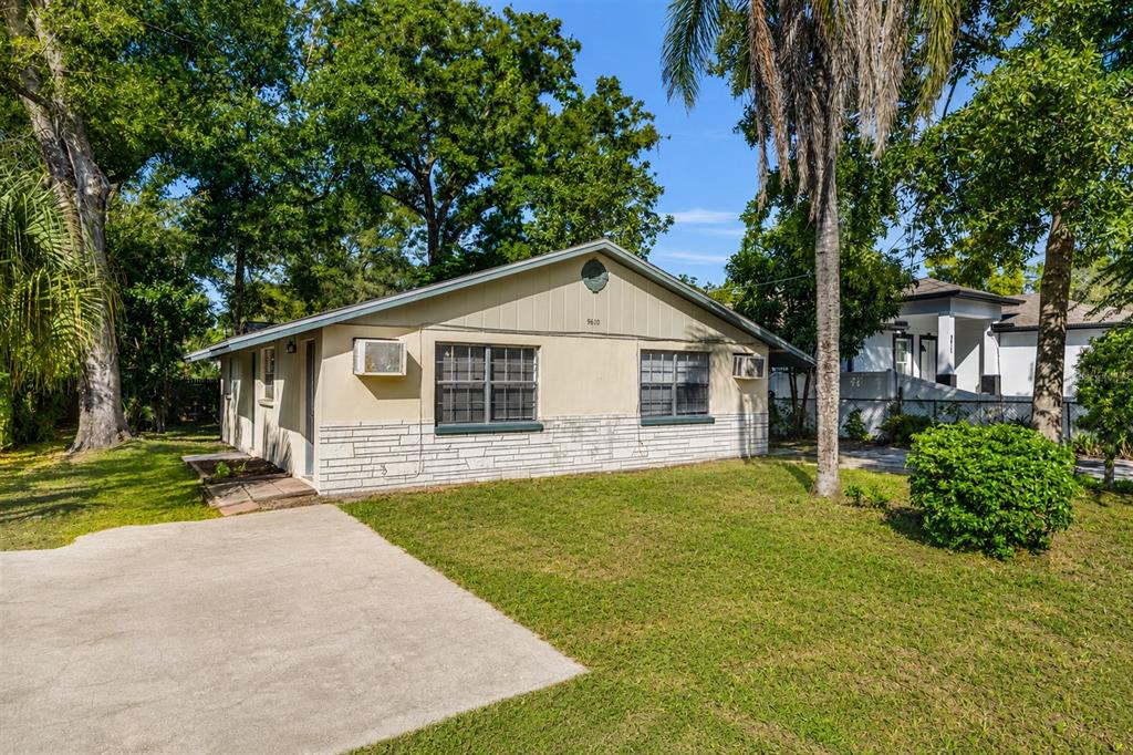 A single-story house with a beige exterior, stone-textured base, and a concrete driveway — 9610 N 12TH STREET, TAMPA, FL