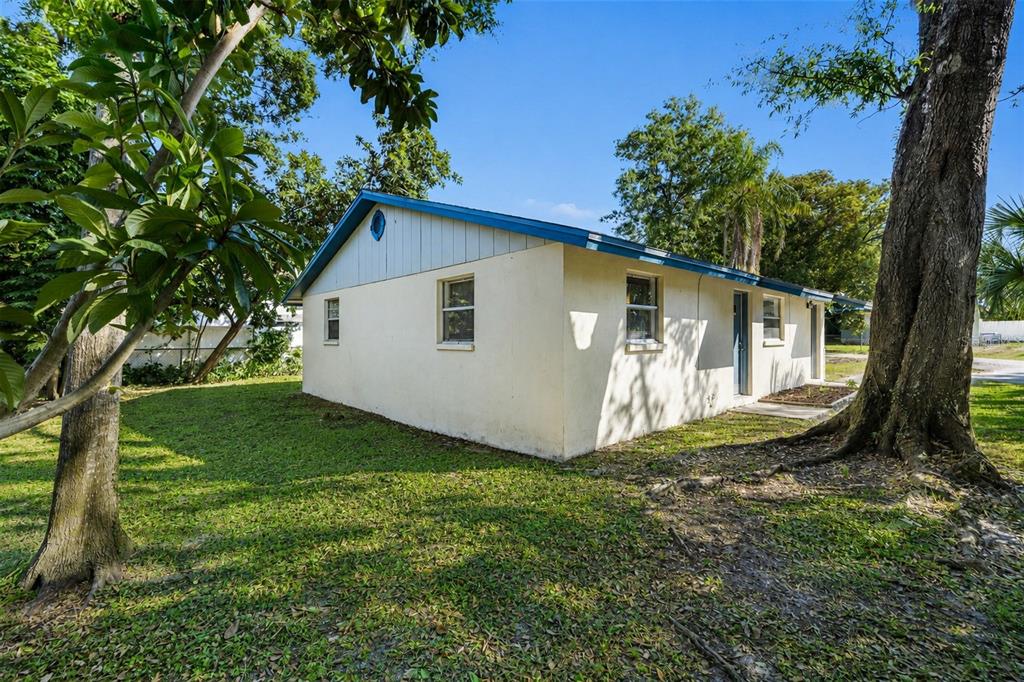 The exterior of a single-story house with light-colored stucco walls and a blue roof — 9610 N 12TH STREET, TAMPA, FL