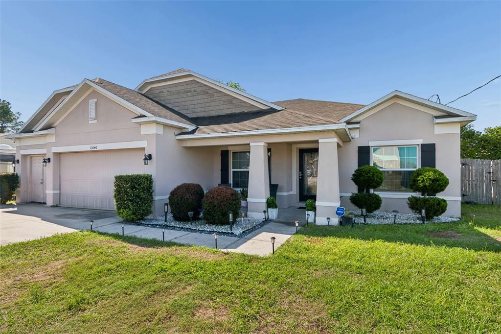 A single-story house with a beige stucco exterior, a two-car garage, and a front porch — 13046 LINDEN DRIVE, SPRING HILL, FL