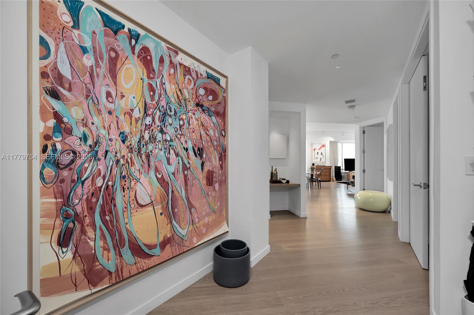 A hallway features light wood flooring, white walls, and a large abstract painting on the left — 1425 Brickell Ave # 61E, Miami FL 33131, MIAMI, FL