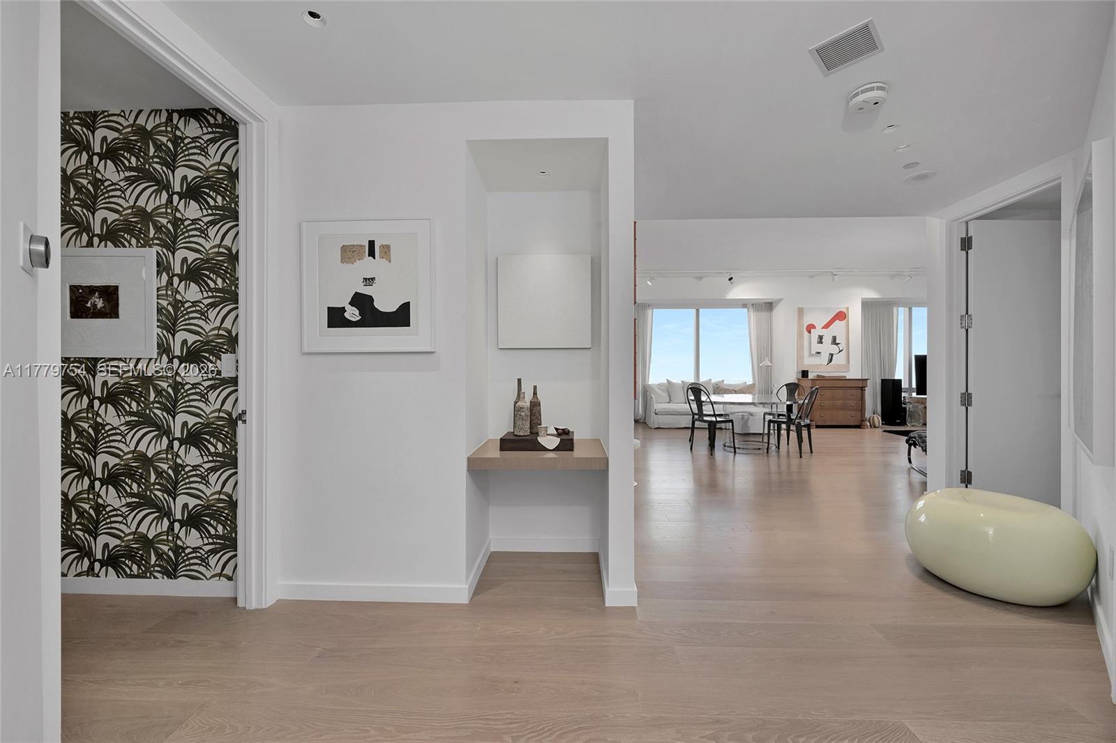 A bright hallway leads to an open-concept living area with light wood flooring and modern decor — 1425 Brickell Ave # 61E, Miami FL 33131, MIAMI, FL