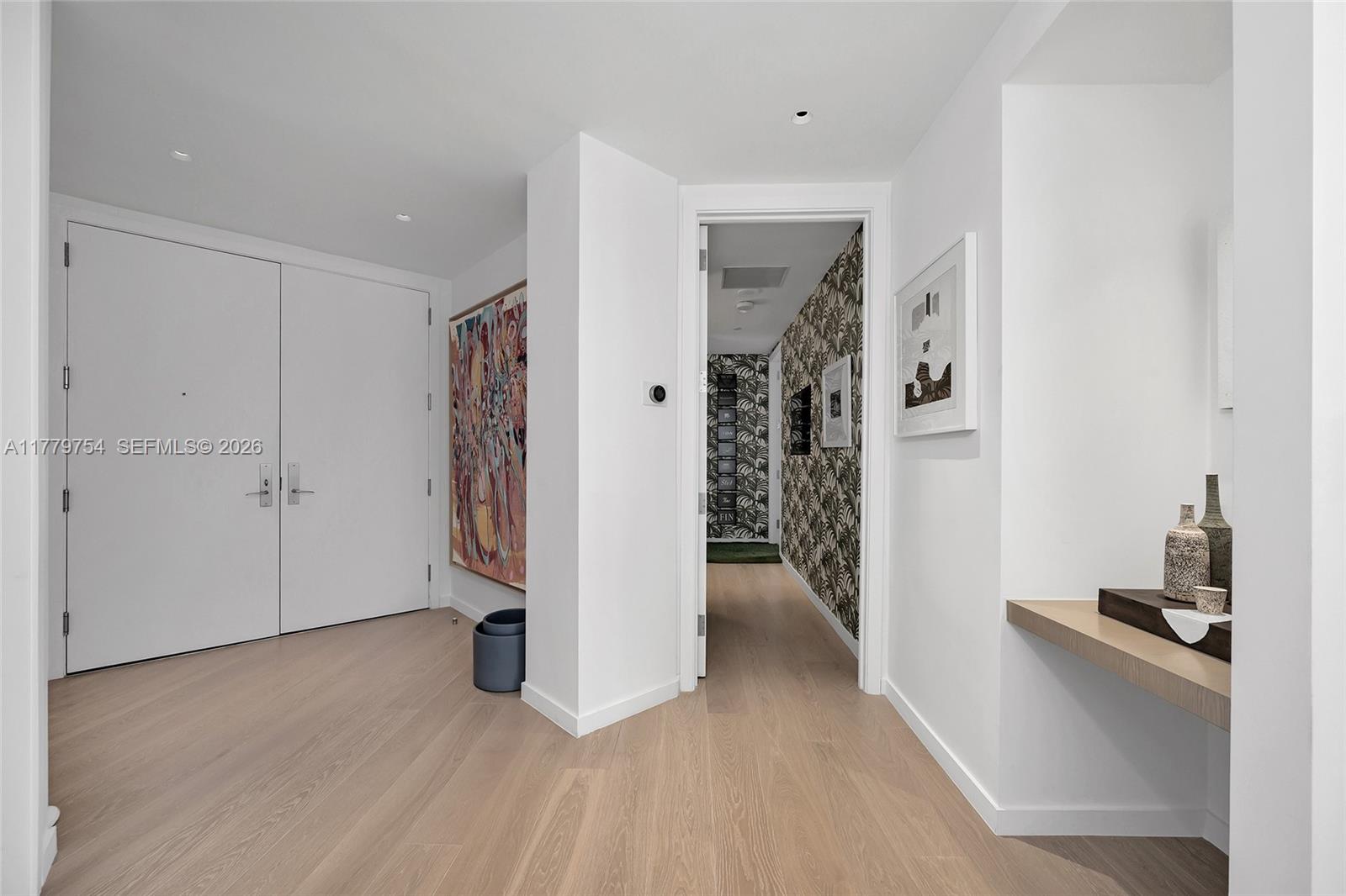 A bright entryway features light wood flooring, white walls, and a patterned wallpapered hallway — 1425 Brickell Ave # 61E, Miami FL 33131, MIAMI, FL