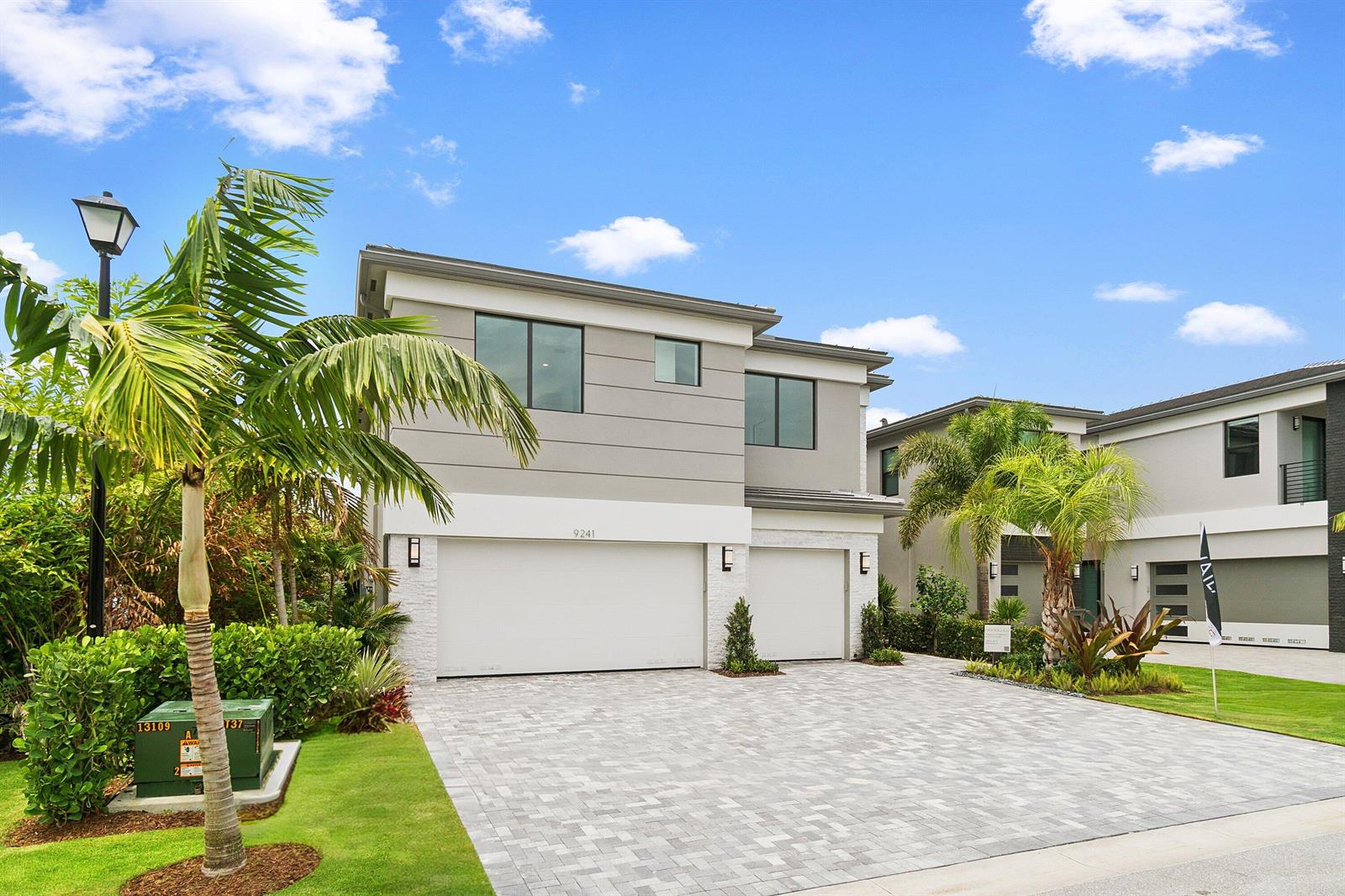 A two-story modern house with a gray facade, white garage doors, and a paved driveway — 9241 Sunflower Meadow Road, Boca Raton FL 33434, BOCA RATON, FL