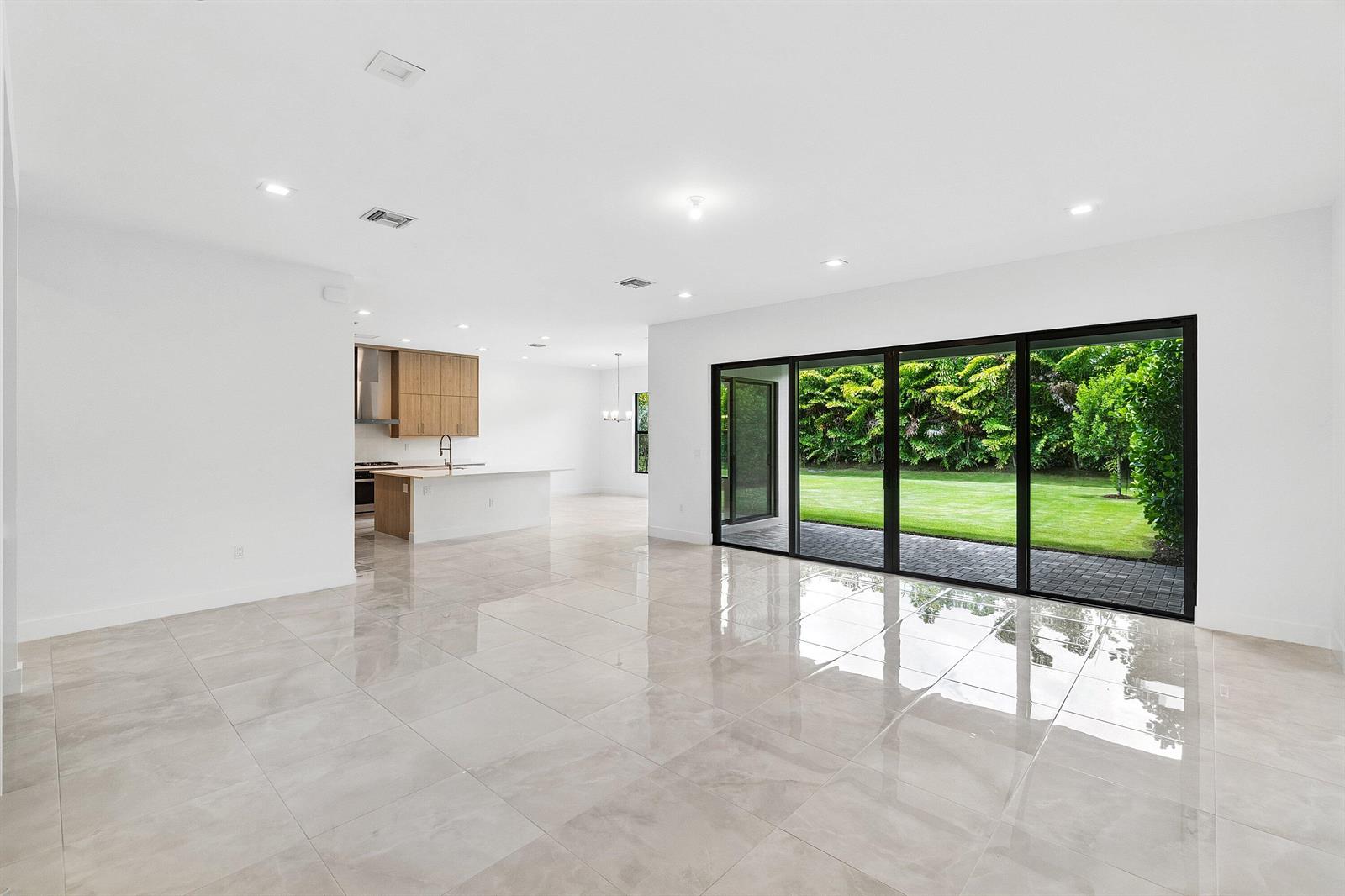 A bright, open-concept living area with large sliding glass doors overlooking a green backyard — 9241 Sunflower Meadow Road, Boca Raton FL 33434, BOCA RATON, FL