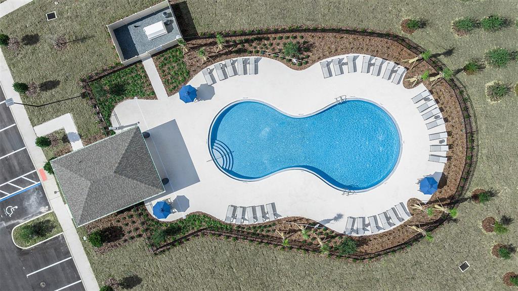An aerial view shows a community swimming pool with a surrounding deck and lounge chairs — 521 MOONSTONE COURT, GROVELAND, FL