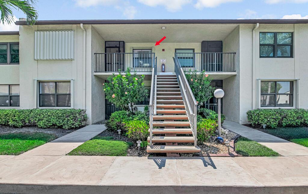 A two-story apartment building exterior features a central staircase leading to an upper-level balcony — 7915 Willow Spring Drive # 1223, Lake Worth FL 33467, LAKE WORTH, FL