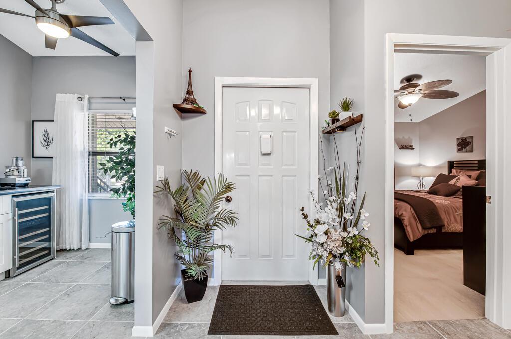 A bright entryway features a white front door, gray walls, tile flooring, and indoor plants — 7915 Willow Spring Drive # 1223, Lake Worth FL 33467, LAKE WORTH, FL
