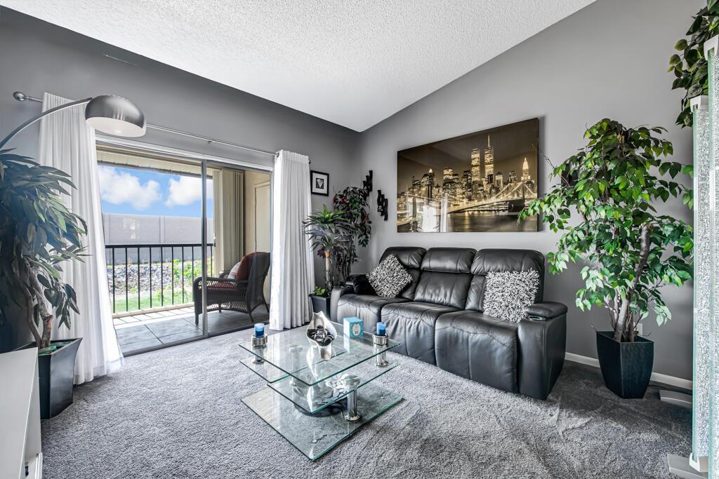 A living room features a black leather sofa, glass coffee table, and a balcony view — 7915 Willow Spring Drive # 1223, Lake Worth FL 33467, LAKE WORTH, FL