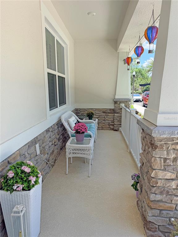 A covered front porch features stone siding, white wicker furniture, and hanging hot air balloon decorations — 1406 BLUMBERG BOULEVARD, WINTER SPRINGS, FL
