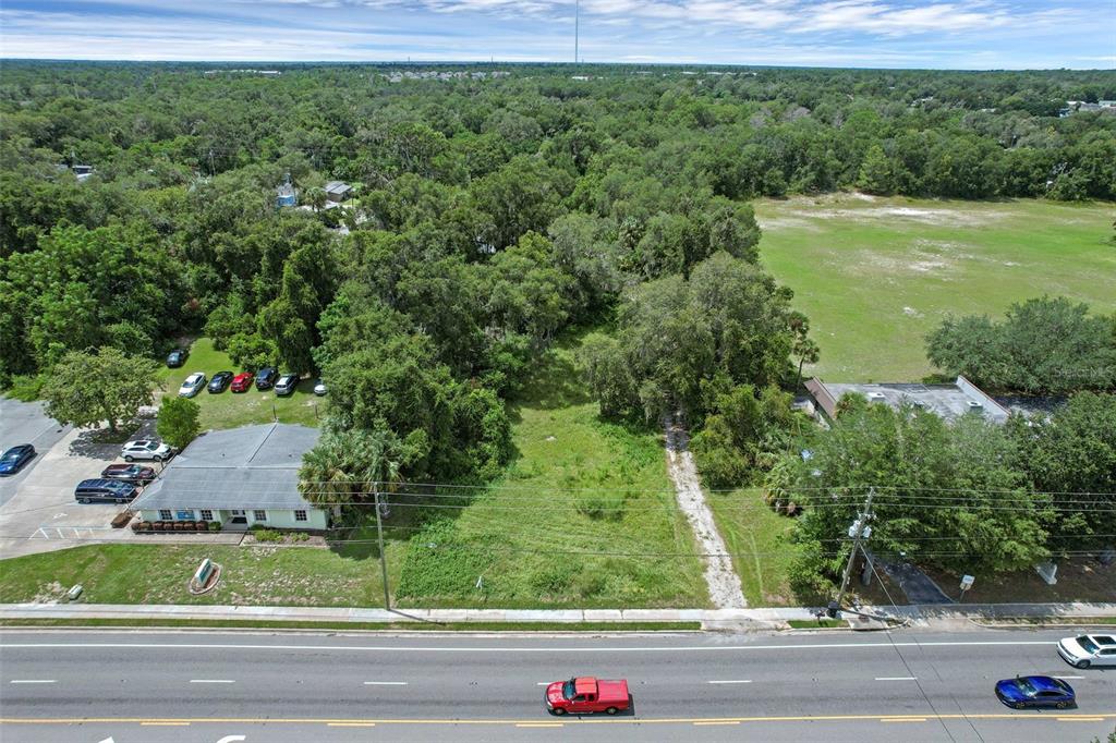 An aerial view shows a vacant lot situated between two commercial buildings along a road — S VOLUSIA AVENUE, ORANGE CITY, FL