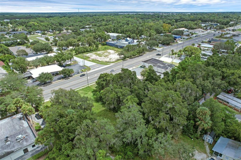 An aerial view shows a vacant lot bordered by a road, trees, and commercial buildings — S VOLUSIA AVENUE, ORANGE CITY, FL