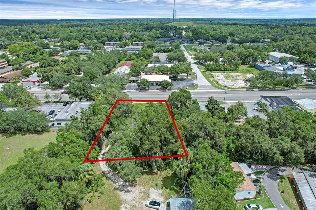 An aerial view shows a wooded, rectangular lot outlined in red near a paved road — S VOLUSIA AVENUE, ORANGE CITY, FL