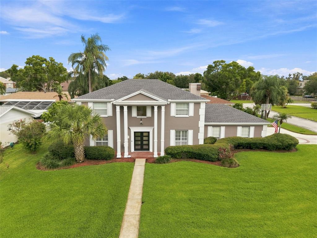 A two-story house with a columned entryway, gray siding, and a large front lawn — 1101 88TH AVENUE N, ST PETERSBURG, FL