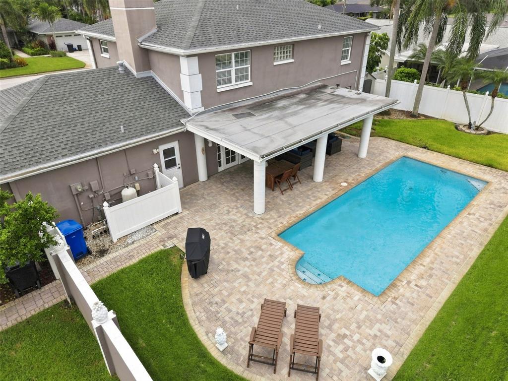 An aerial view of a backyard featuring a swimming pool, a covered patio, and pavers — 1101 88TH AVENUE N, ST PETERSBURG, FL