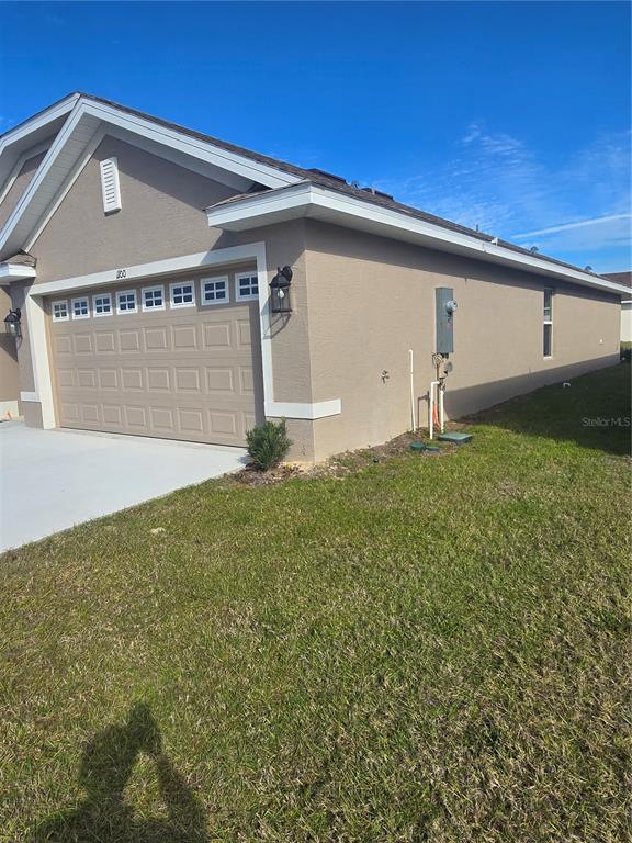 The exterior of a tan house features a two-car garage and a side yard — 1100 HERON POINT DRIVE, INVERNESS, FL
