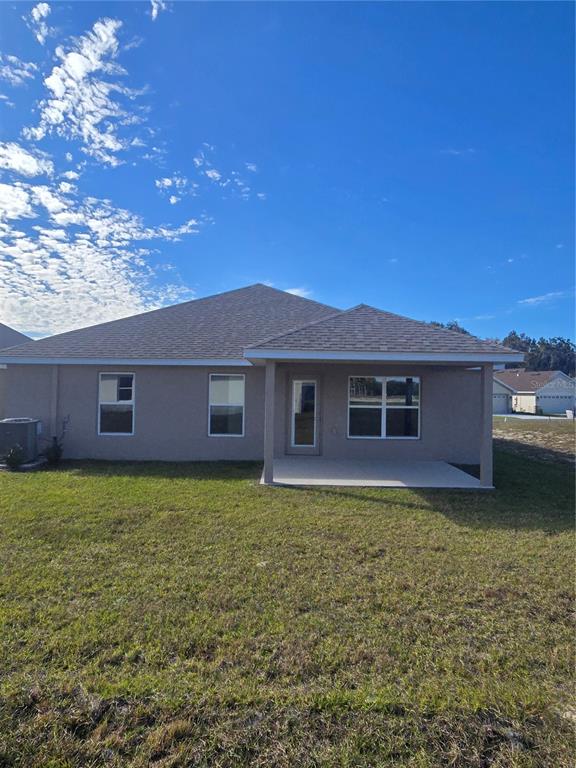 The exterior rear view of a single-story house features a covered patio and lawn — 1100 HERON POINT DRIVE, INVERNESS, FL