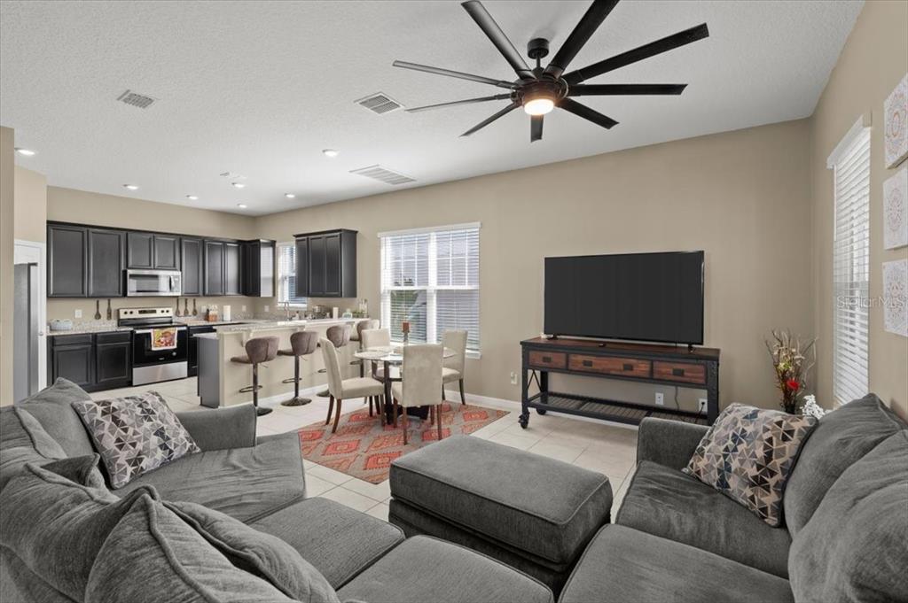 An open-concept living room and kitchen featuring dark cabinetry, a sectional sofa, and dining area — 2916 MELETO BOULEVARD, NEW SMYRNA BEACH, FL