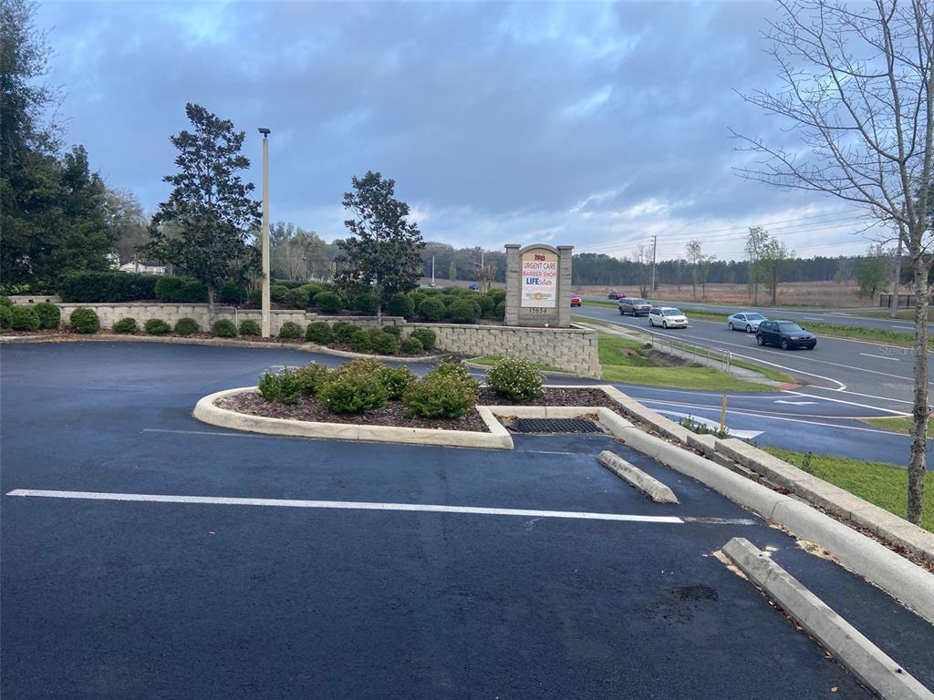 A paved parking lot features a landscaped island and a monument sign near a road — 15634 NW US HIGHWAY 441 UNIT D, ALACHUA, FL