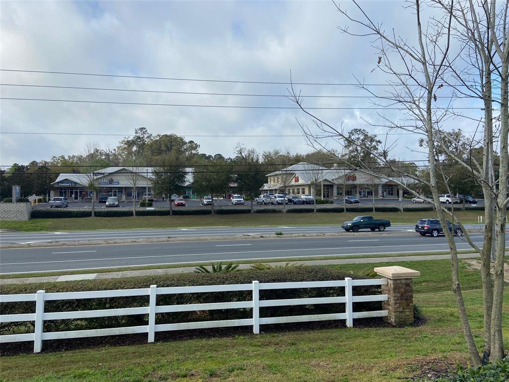 A view of a commercial strip mall across a multi-lane road with a white fence — 15634 NW US HIGHWAY 441 UNIT D, ALACHUA, FL