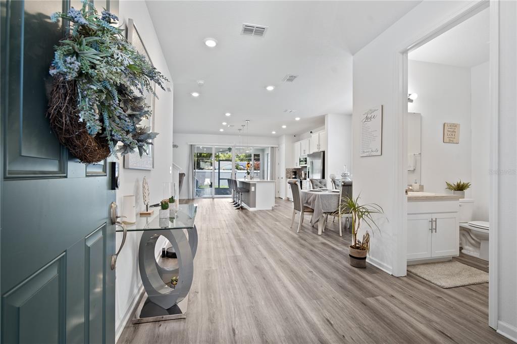 An entryway leads into an open-concept living area with light wood flooring and a bathroom — 1125 MATTIE POINTE BOULEVARD, AUBURNDALE, FL
