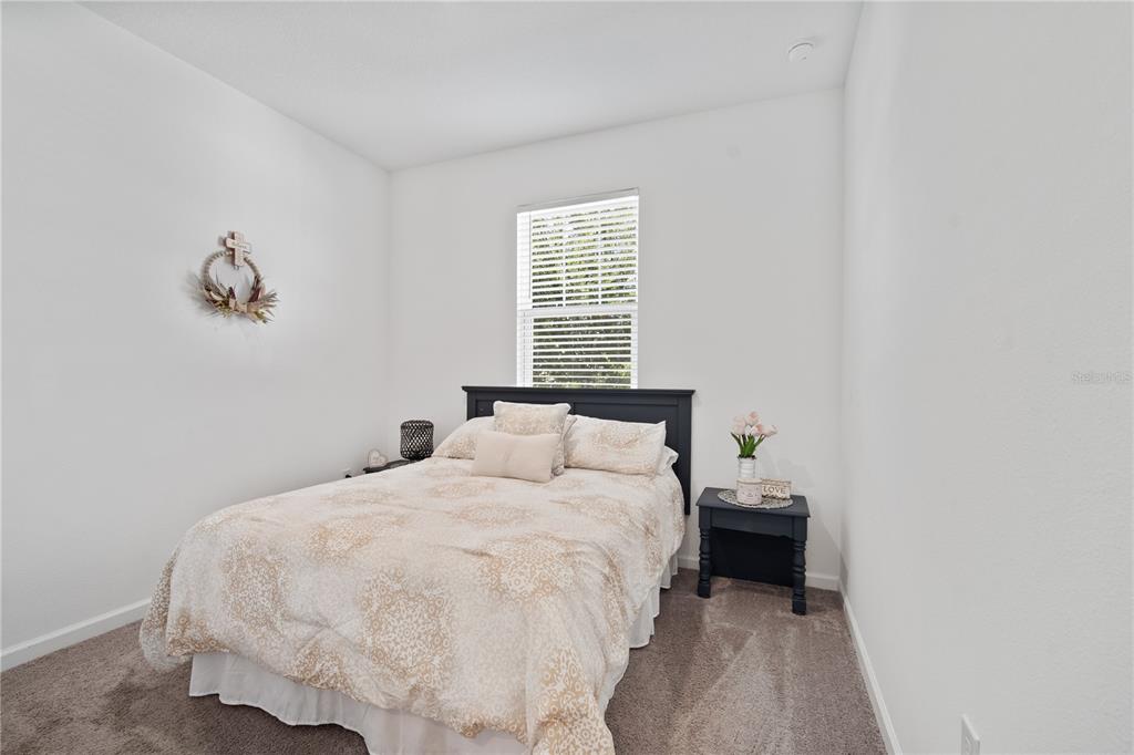 A bedroom features a bed with a patterned comforter, a dark headboard, and two nightstands — 1125 MATTIE POINTE BOULEVARD, AUBURNDALE, FL