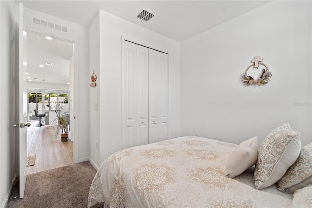 A bedroom with carpeted flooring, a white closet, and a doorway leading to a kitchen — 1125 MATTIE POINTE BOULEVARD, AUBURNDALE, FL