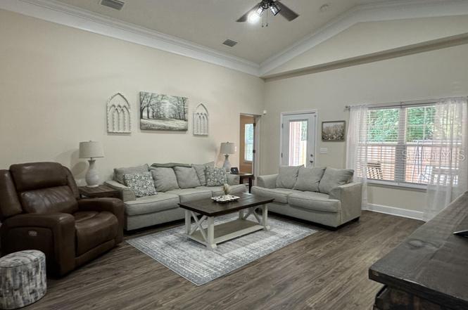 A living room features a brown recliner, two gray sofas, and a wooden coffee table — 6107 W 1ST MNR, PALATKA, FL