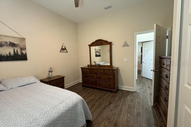 A bedroom features a bed, a wooden dresser with a mirror, and wood-look flooring — 6107 W 1ST MNR, PALATKA, FL