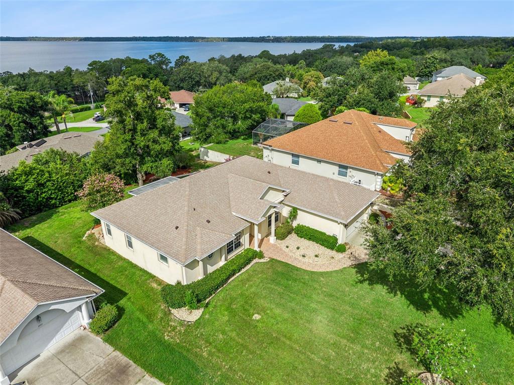 An aerial view shows a suburban house with a tan roof and lawn near water — 10308 CALLE DE FLORES DRIVE, CLERMONT, FL