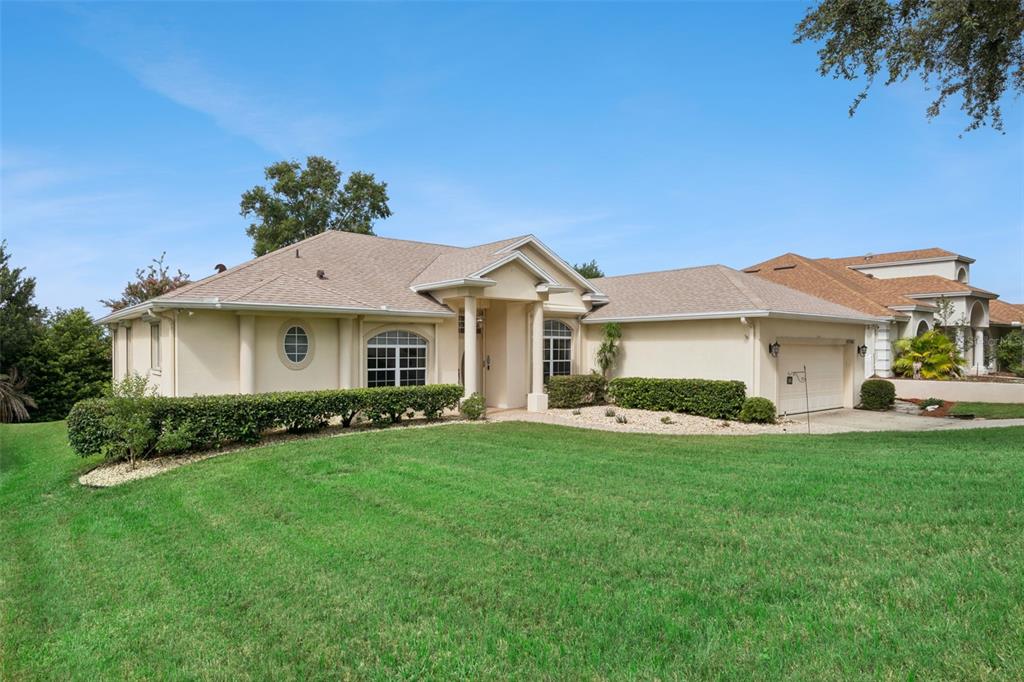 A single-story house with a tan exterior, a shingled roof, and a front-facing garage — 10308 CALLE DE FLORES DRIVE, CLERMONT, FL