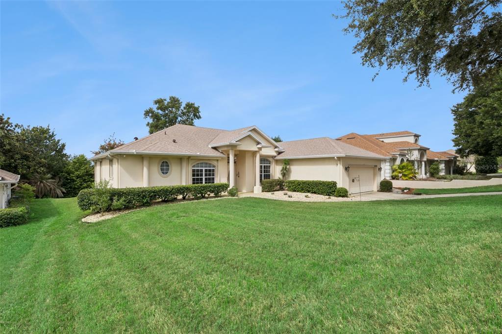 A single-story beige house with a tan shingled roof and a large front lawn — 10308 CALLE DE FLORES DRIVE, CLERMONT, FL