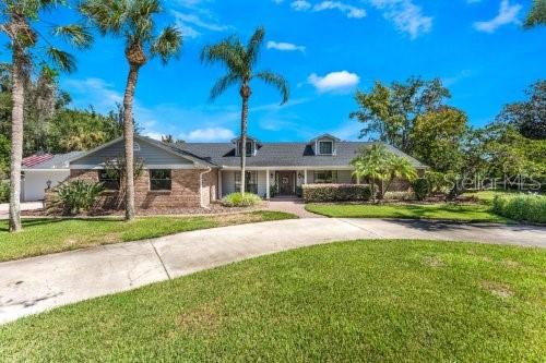 A single-story house with a gray roof and a curved driveway sits on a lawn — 306 N SWEETWATER COVE BOULEVARD, LONGWOOD, FL