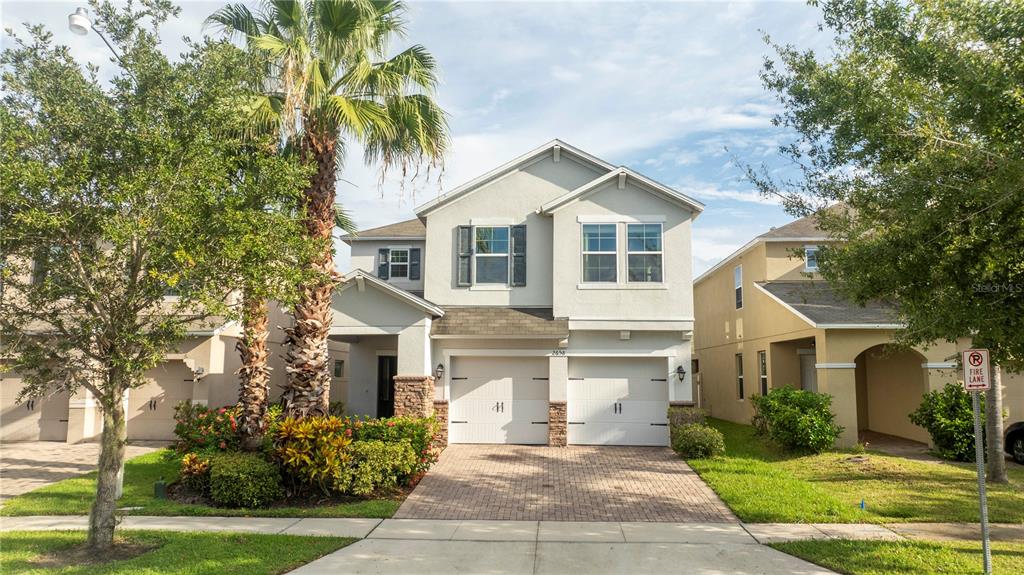 A two-story suburban house with a two-car garage, stone accents, and a paved driveway — 2658 SAN SIMEON WAY, KISSIMMEE, FL