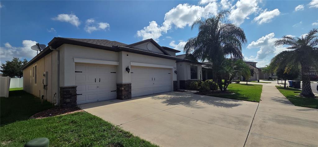 A single-story house with a two-car garage, stone accents, and a palm tree in front — 13807 FELIX WILL ROAD, RIVERVIEW, FL