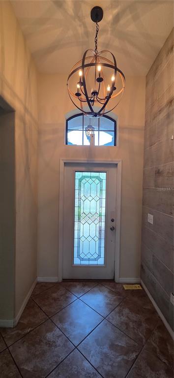 An entryway features a globe chandelier, a front door with decorative glass, and tiled flooring — 13807 FELIX WILL ROAD, RIVERVIEW, FL