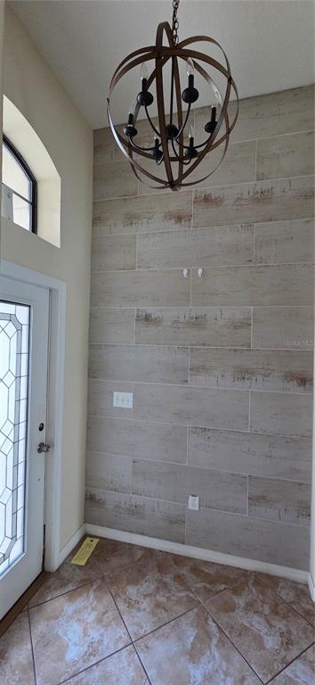 An entryway features a wood-look tile accent wall, a globe chandelier, and tiled flooring — 13807 FELIX WILL ROAD, RIVERVIEW, FL