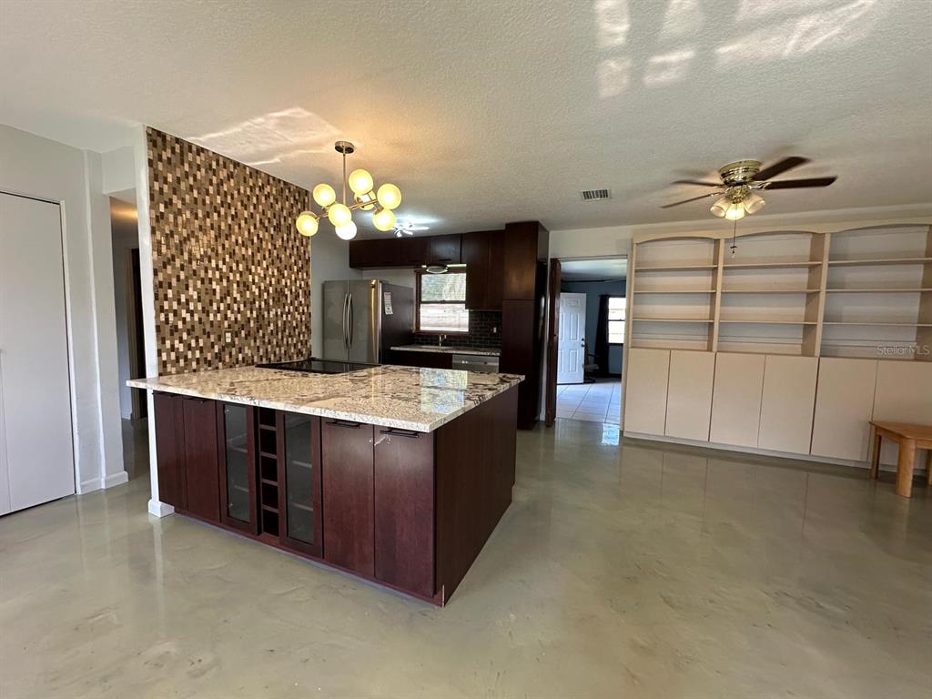 A kitchen with a large island, dark wood cabinets, and a mosaic tile accent wall — 1508 MONA AVENUE, OCOEE, FL