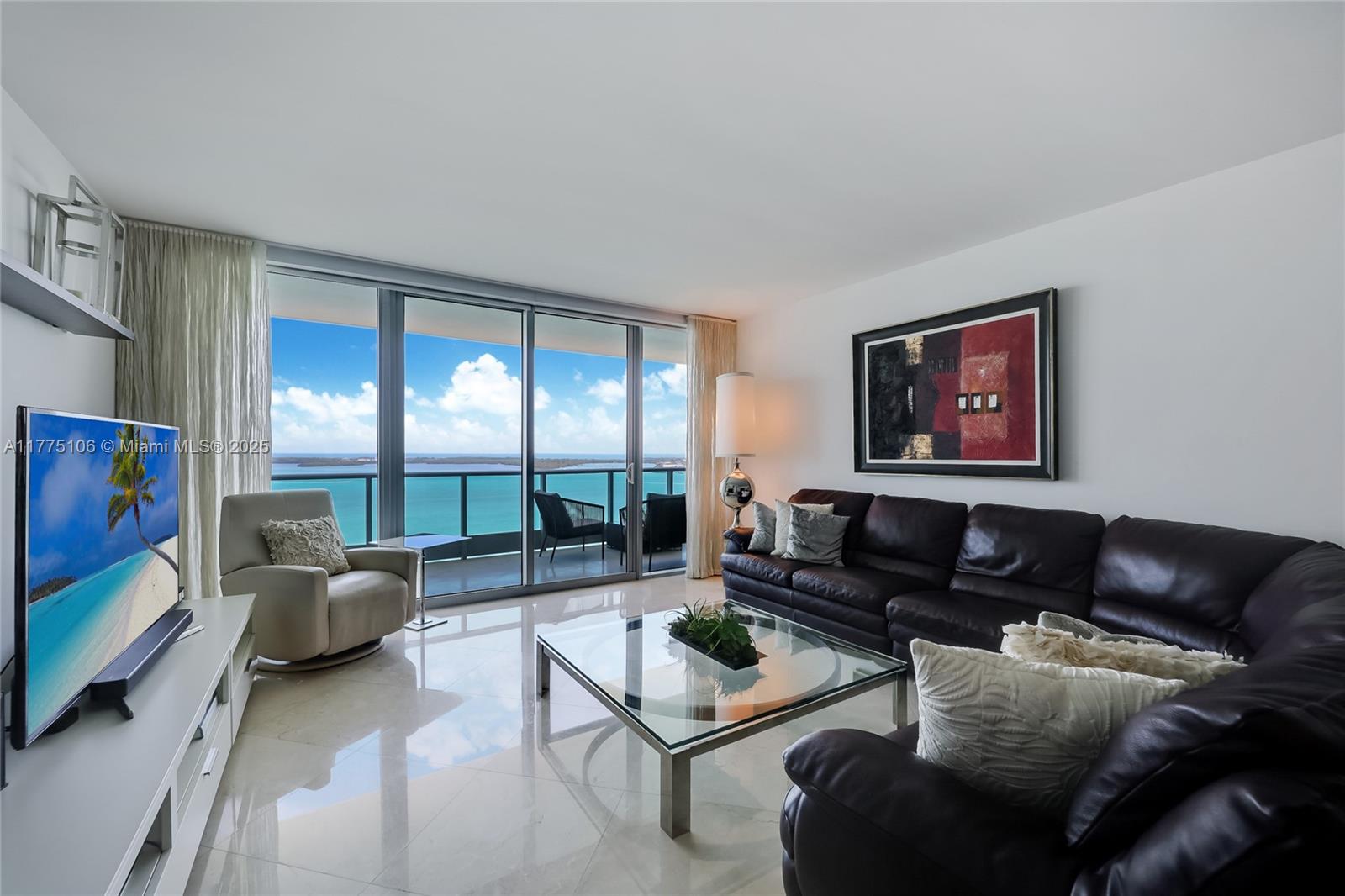 A living room features a dark leather sectional, glass coffee table, and floor-to-ceiling ocean views — 1331 Brickell Bay Dr # 2605, Miami FL 33131, MIAMI, FL