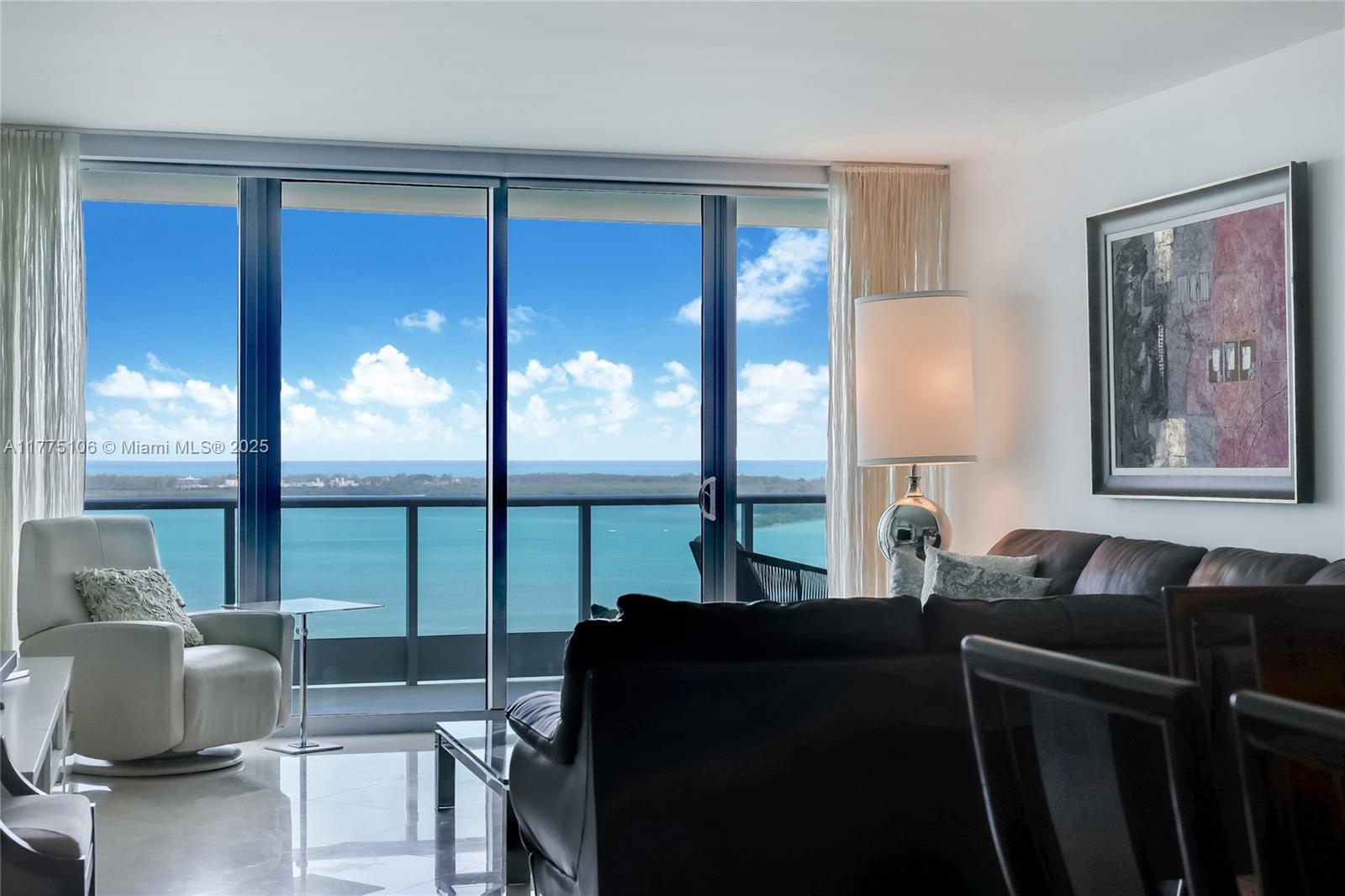 A living room features a dark leather sofa, a white armchair, and floor-to-ceiling ocean views — 1331 Brickell Bay Dr # 2605, Miami FL 33131, MIAMI, FL
